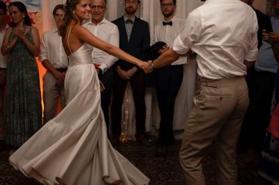 Façade d'une maison provençale jaune à volets verts, éclairée par le soleil couchant, avec une cour pavée et des plantes.