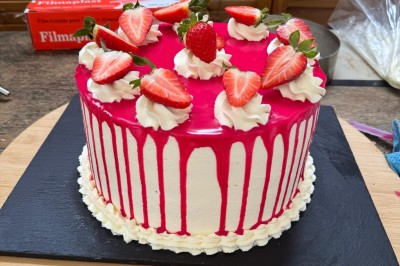 Borne photo interactive éclairée entourée de poteaux dorés et cordons rouges sur un tapis rouge dans une salle lumineuse.