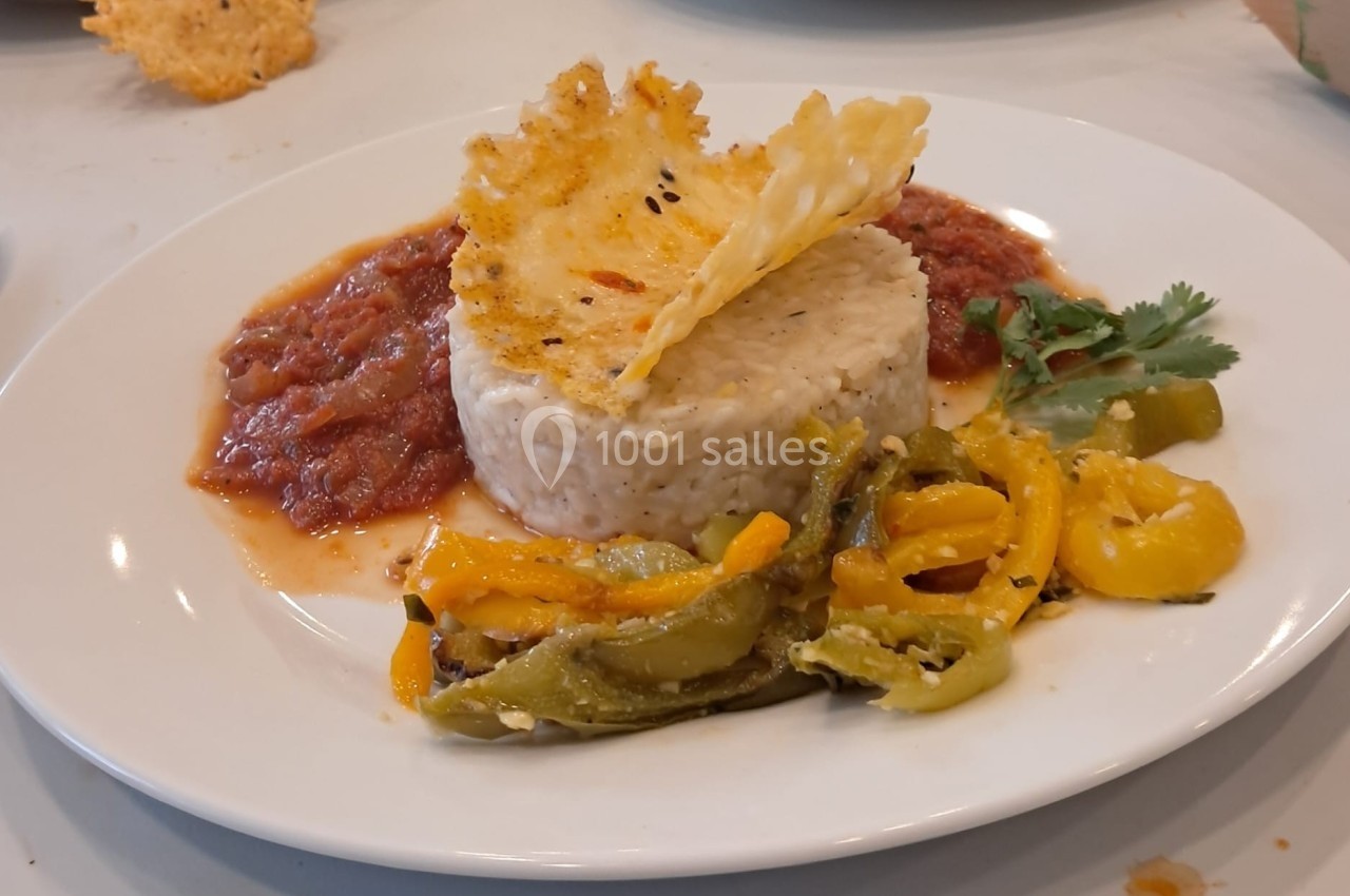 Assiette de riz accompagné de légumes sautés, sauce tomate et décorée d'une tuile de fromage croustillante.