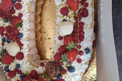 Borne photo interactive éclairée entourée de poteaux dorés et cordons rouges sur un tapis rouge dans une salle lumineuse.