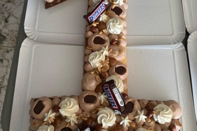 Borne photo interactive éclairée entourée de poteaux dorés et cordons rouges sur un tapis rouge dans une salle lumineuse.