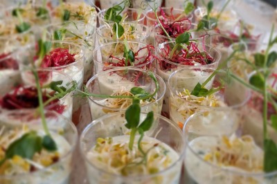 Borne photo interactive éclairée entourée de poteaux dorés et cordons rouges sur un tapis rouge dans une salle lumineuse.