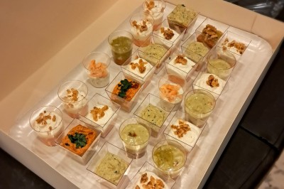 Borne photo interactive éclairée entourée de poteaux dorés et cordons rouges sur un tapis rouge dans une salle lumineuse.