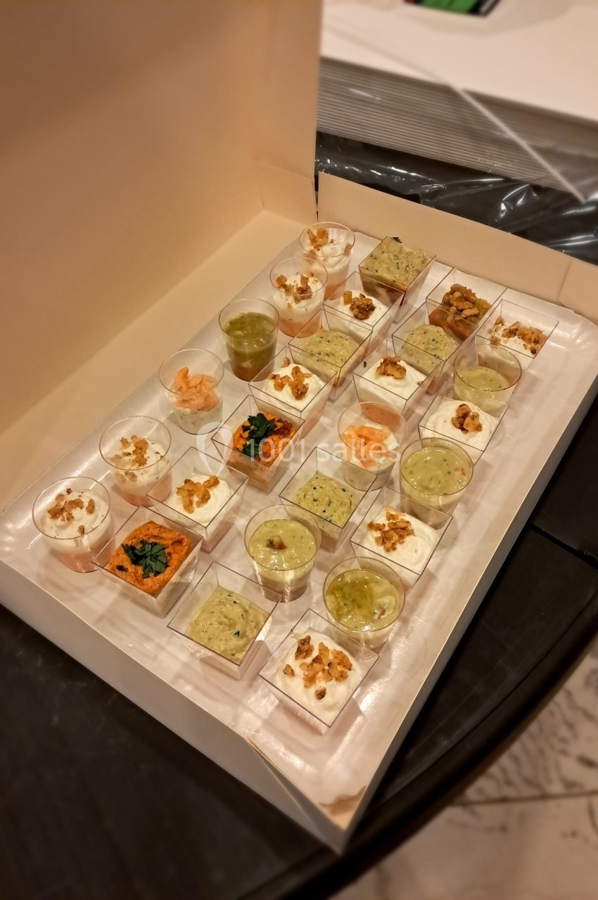 Plateau de verrines variées comprenant des préparations salées et sucrées, disposées dans une boîte ouverte.