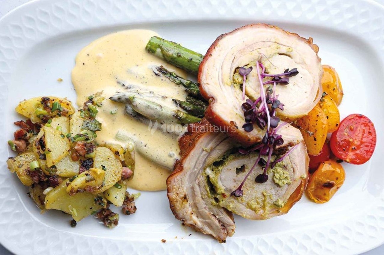 Assiette composée de rôti farci, asperges nappées de sauce, légumes rôtis et salade de pommes de terre.