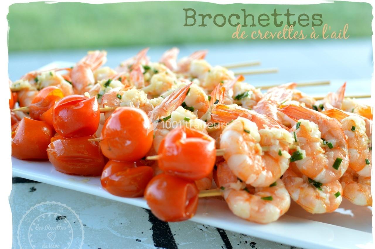Brochettes de crevettes et tomates cerises grillées, assaisonnées à l'ail et aux herbes, présentées sur une assiette blanche.