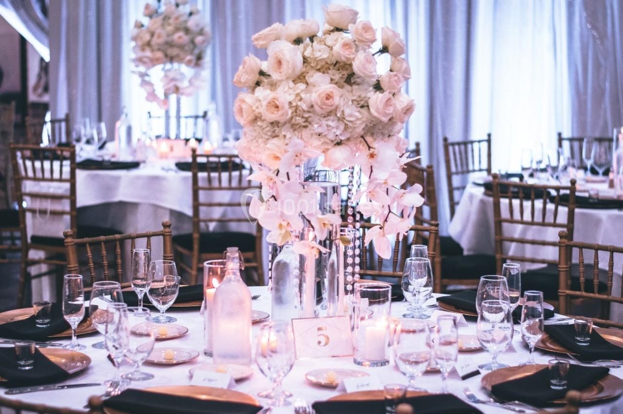 Table de réception élégamment dressée avec un centre de table floral blanc, entourée de chaises dorées.