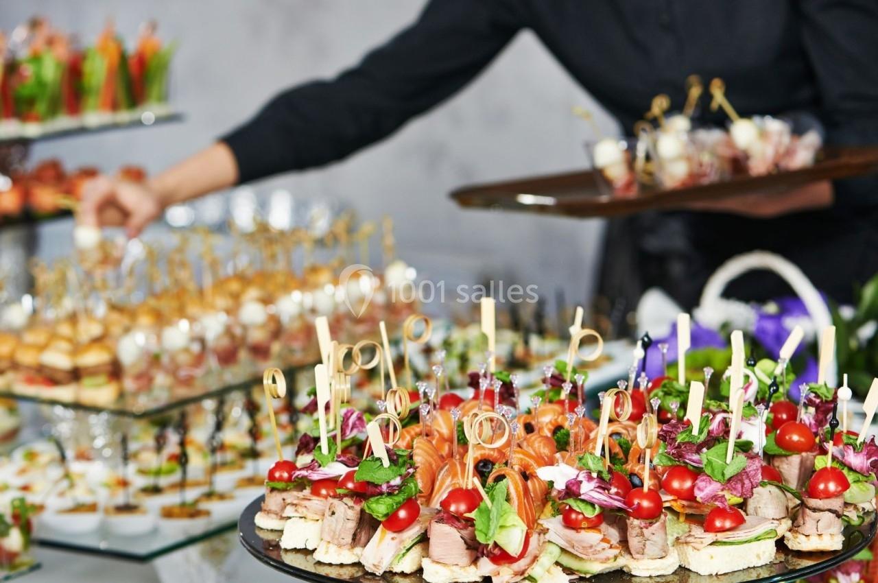 Plateau de canapés variés avec légumes, saumon et garnitures, présenté sur une table lors d'un buffet.