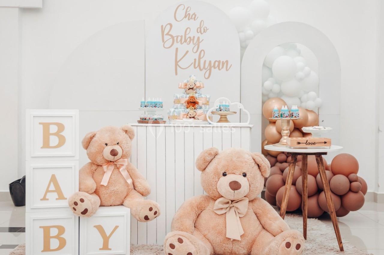 Décoration de fête avec des ours en peluche, des ballons blancs et marron, et des cubes affichant le mot ’BABY’.
