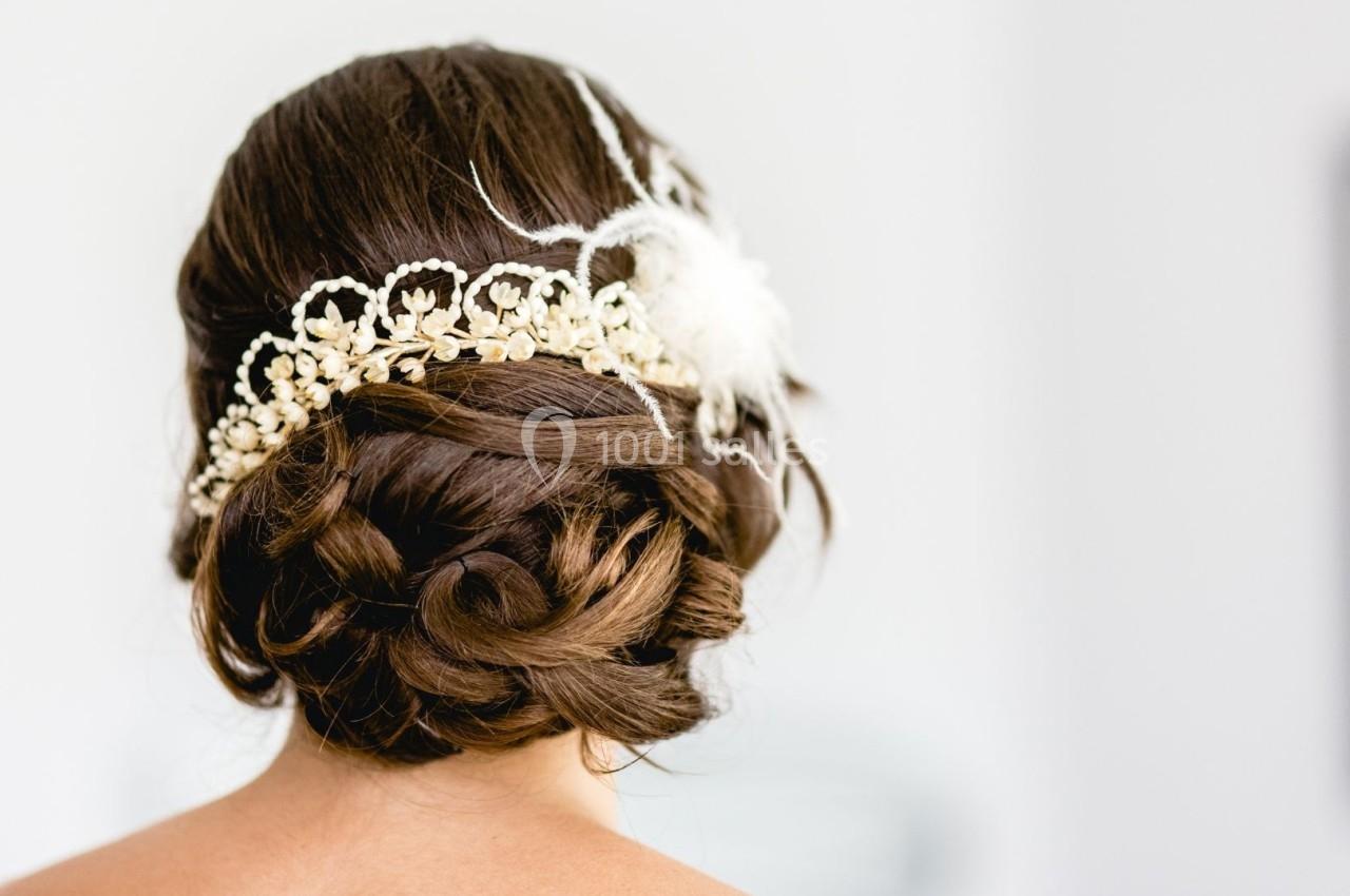 Chignon brun élégant orné d'un accessoire floral blanc et de perles, vu de dos.