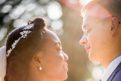Femme en robe blanche souriante, assise près d'une fontaine, avec un homme en costume visible de dos.