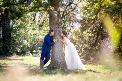 Femme en robe blanche souriante, assise près d'une fontaine, avec un homme en costume visible de dos.