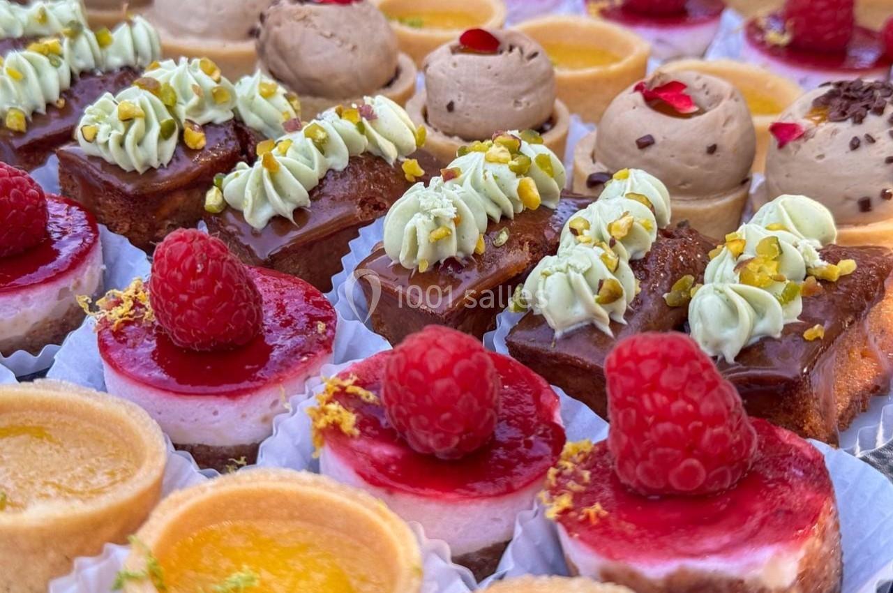 Assortiment de pâtisseries miniatures avec fruits, crèmes et décorations colorées disposées sur un plateau.