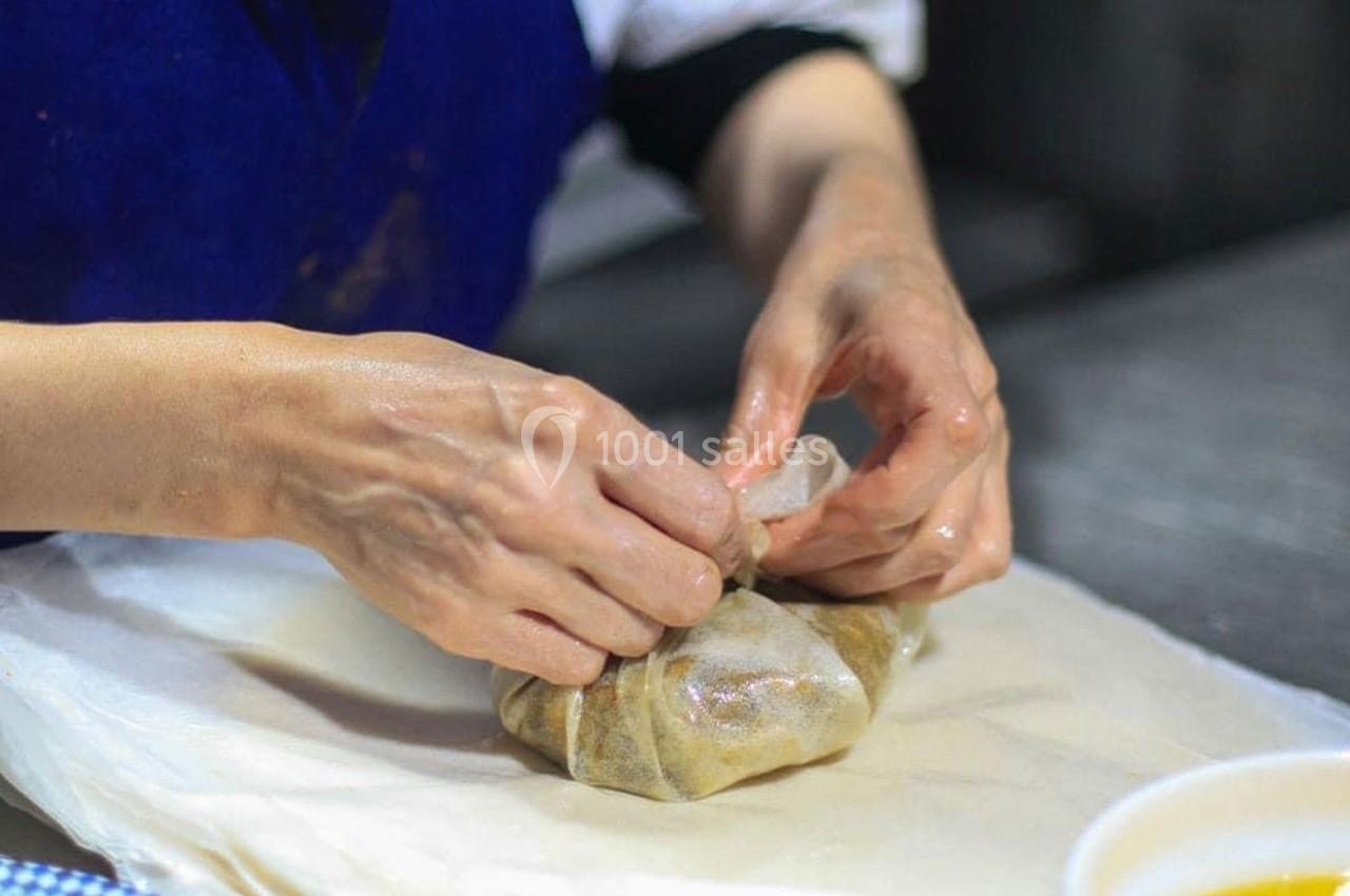 Une personne enveloppe soigneusement un aliment dans un tissu, sur une surface de travail en cuisine.
