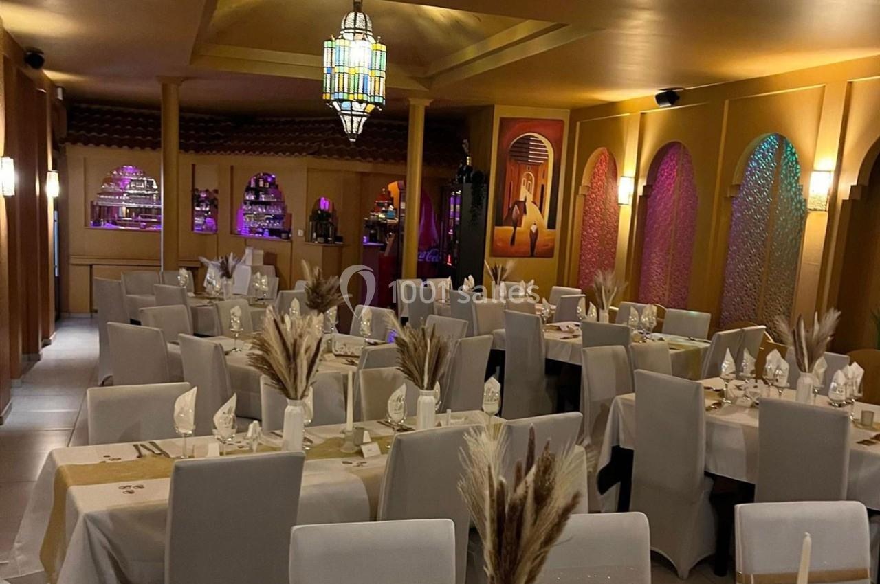 Salle de restaurant décorée dans des tons chauds, avec tables dressées et éclairage tamisé.