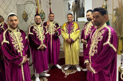 Miniature Location salle Liège (Liège) - Le Numidie #21 Un groupe d'hommes en tenues traditionnelles pose devant une décoration orientale et une affiche promotionnelle.