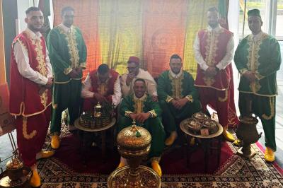 Miniature Location salle Liège (Liège) - Le Numidie #22 Un groupe d'hommes en tenues traditionnelles pose devant une décoration orientale et une affiche promotionnelle.