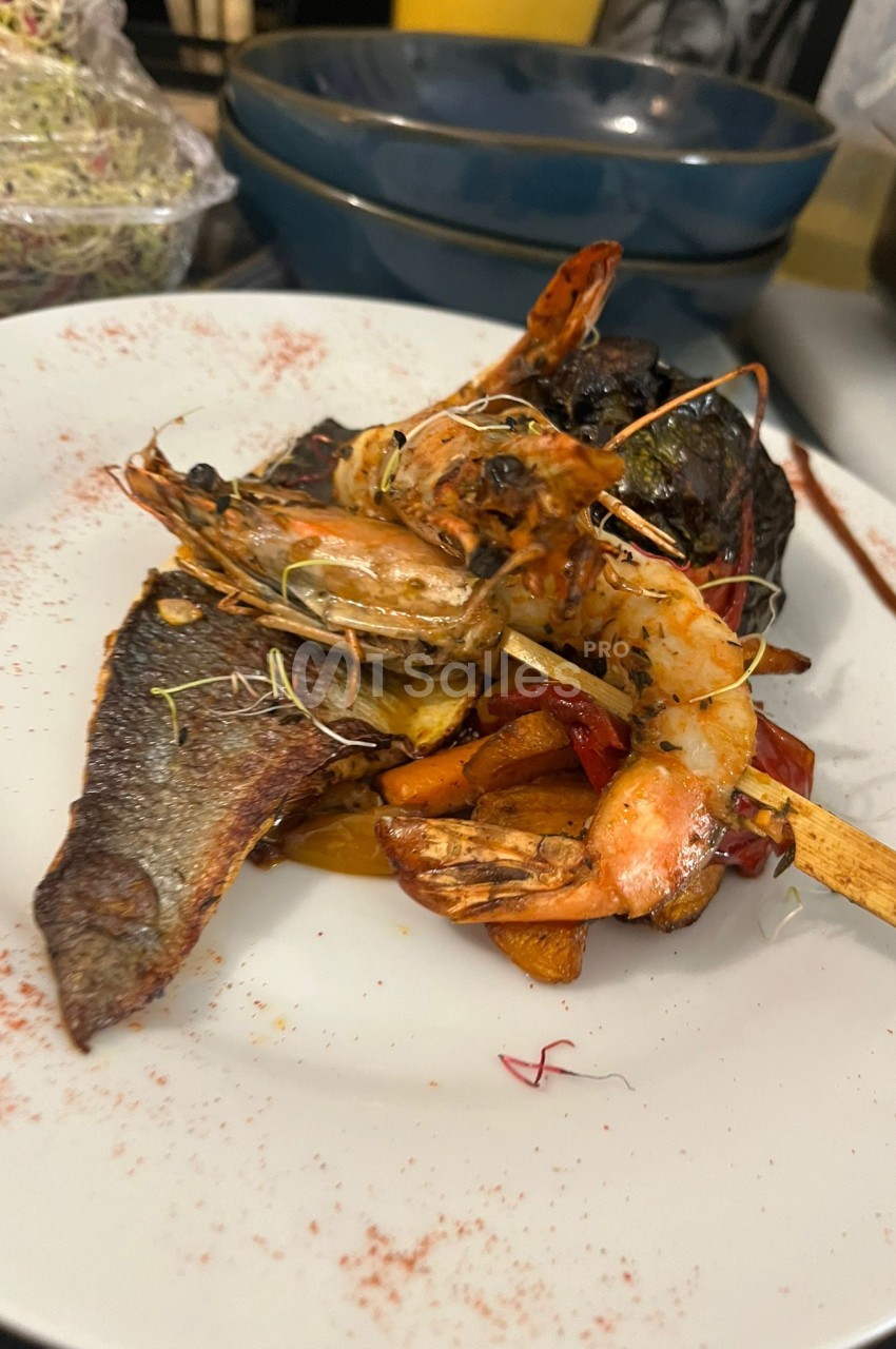 Assiette blanche avec homard, crevettes et poisson rôtis garnis de légumes et herbes aromatiques.