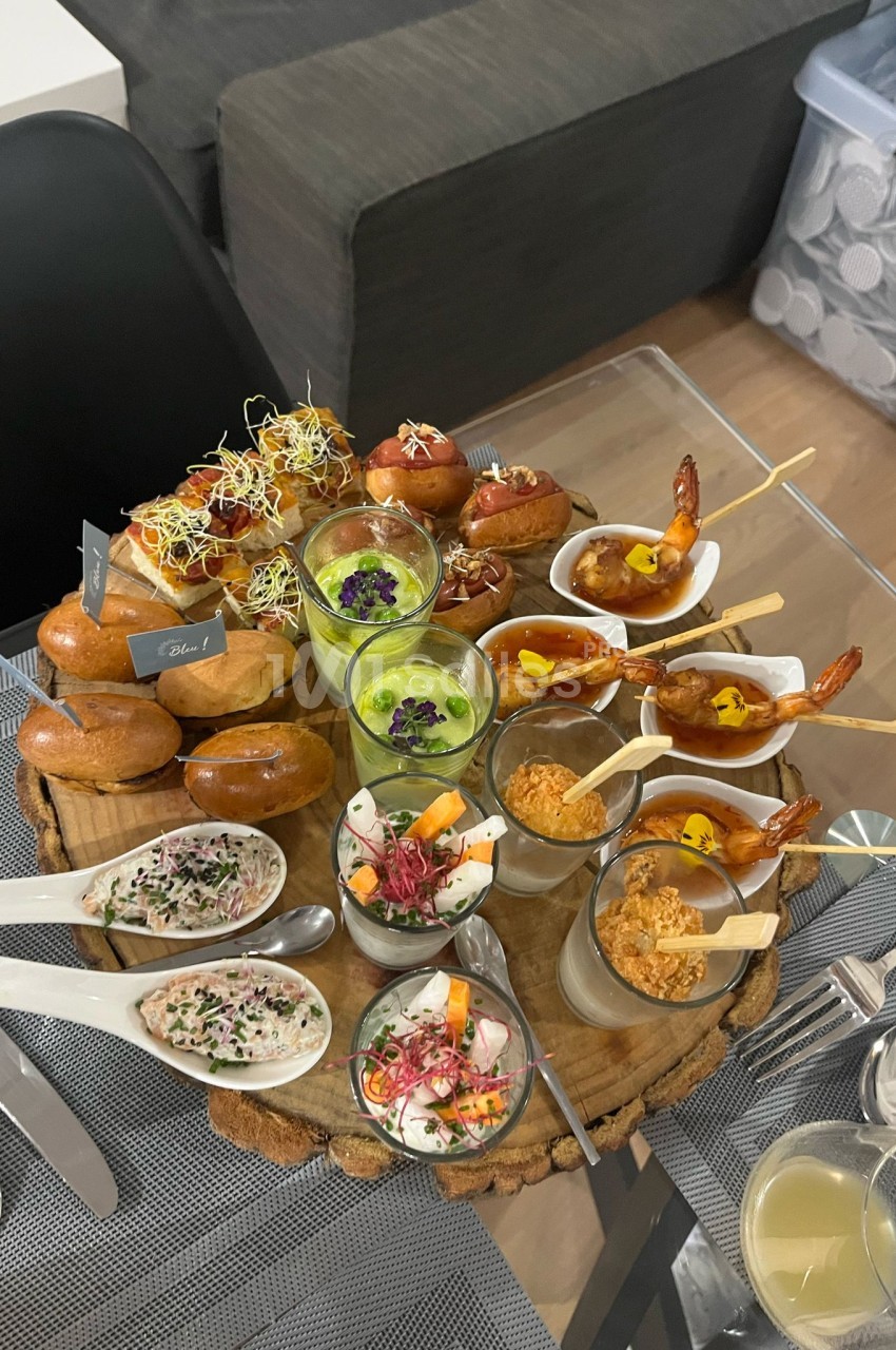 Plateau de dégustation traiteur avec pains, crevettes brochettes, verrines et sauces, sur table dressée.