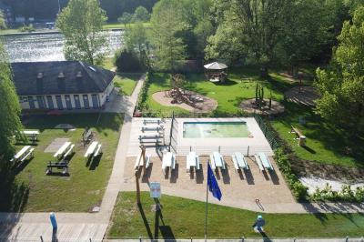 Miniature Location salle Yvoir (Namur) - L’île d’Yvoir  #3 Aire de jeux en bois sur un sol sablé, entourée de verdure et située près d'une rivière et de collines.