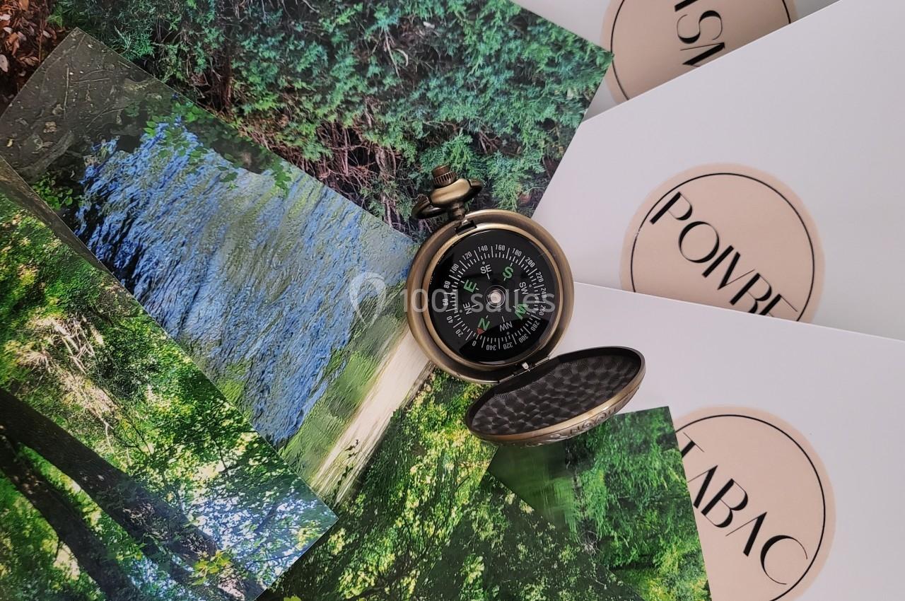 Boussole ancienne ouverte posée sur des photos de paysages naturels et des enveloppes avec des logos imprimés.