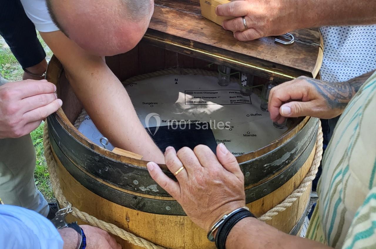 Un groupe de personnes manipule un tonneau en bois ouvert, observant ou ajustant son contenu.
