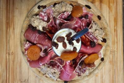 Intérieur d'un bar cosy avec un comptoir en bois, des tabourets hauts et des tables alignées dans un espace chaleureux.