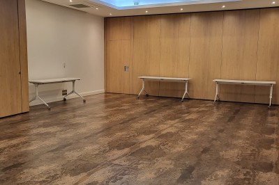 Intérieur d'un bar cosy avec un comptoir en bois, des tabourets hauts et des tables alignées dans un espace chaleureux.