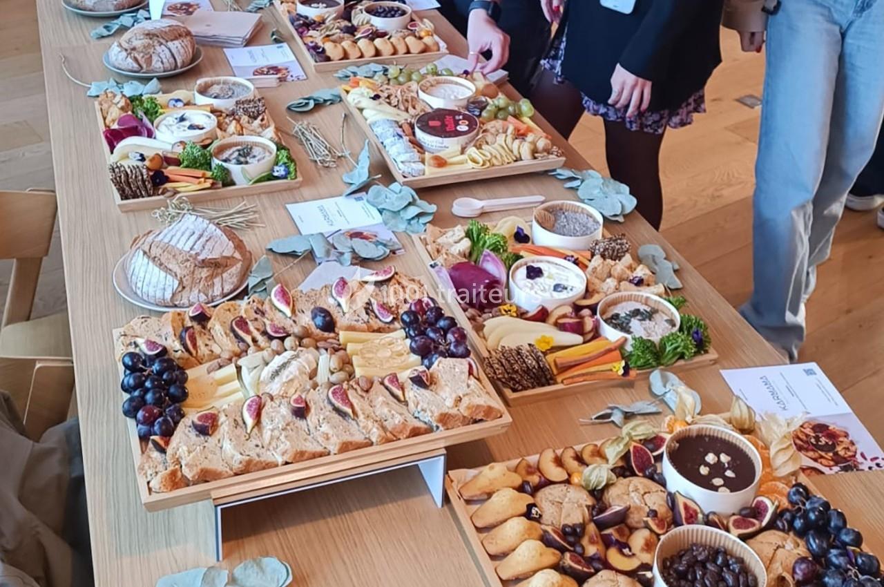 Table garnie de plateaux de charcuterie, fromages, fruits, pains et dips, entourée de convives.