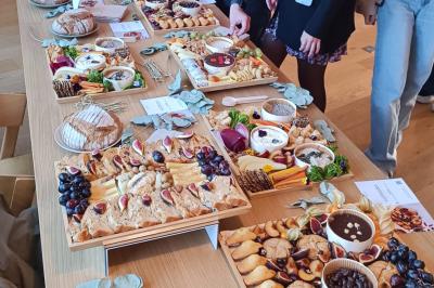 Plateau coloré de crudités, fromages, dips, fruits secs et fleurs comestibles disposés de manière artistique.