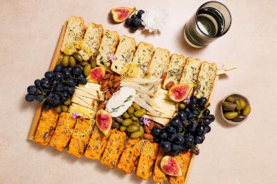 Plateau coloré de crudités, fromages, dips, fruits secs et fleurs comestibles disposés de manière artistique.