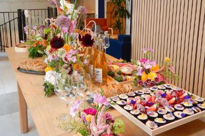 Plateau coloré de crudités, fromages, dips, fruits secs et fleurs comestibles disposés de manière artistique.