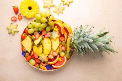 Plateau coloré de crudités, fromages, dips, fruits secs et fleurs comestibles disposés de manière artistique.