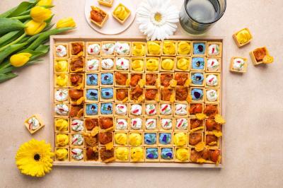 Plateau coloré de crudités, fromages, dips, fruits secs et fleurs comestibles disposés de manière artistique.