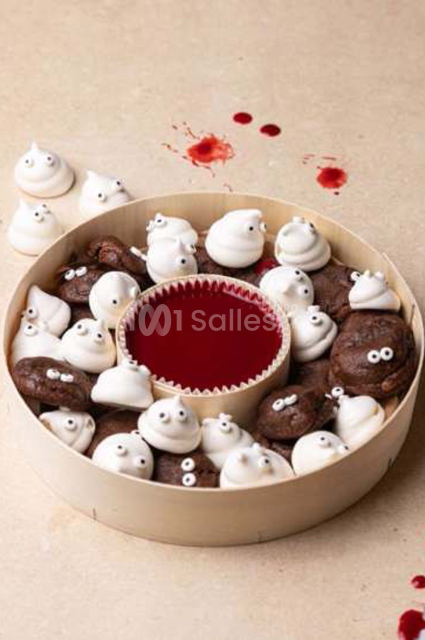 Plateau rond en bois garni de meringues blanches décorées d'yeux en sucre et de petits gâteaux au chocolat ressemblant à des crottes, autour d'un bol de gelée rouge. Let me check length: roughly 165 characters - too long. Need ≤125. Plateau rond en bois