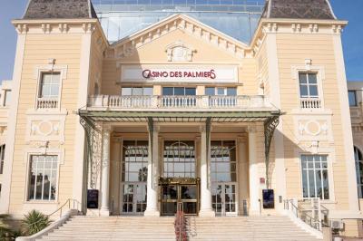 Deux machines à sous lumineuses avec écrans colorés, une personne assise devant l'une d'elles dans un casino.