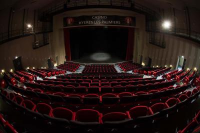 Deux machines à sous lumineuses avec écrans colorés, une personne assise devant l'une d'elles dans un casino.