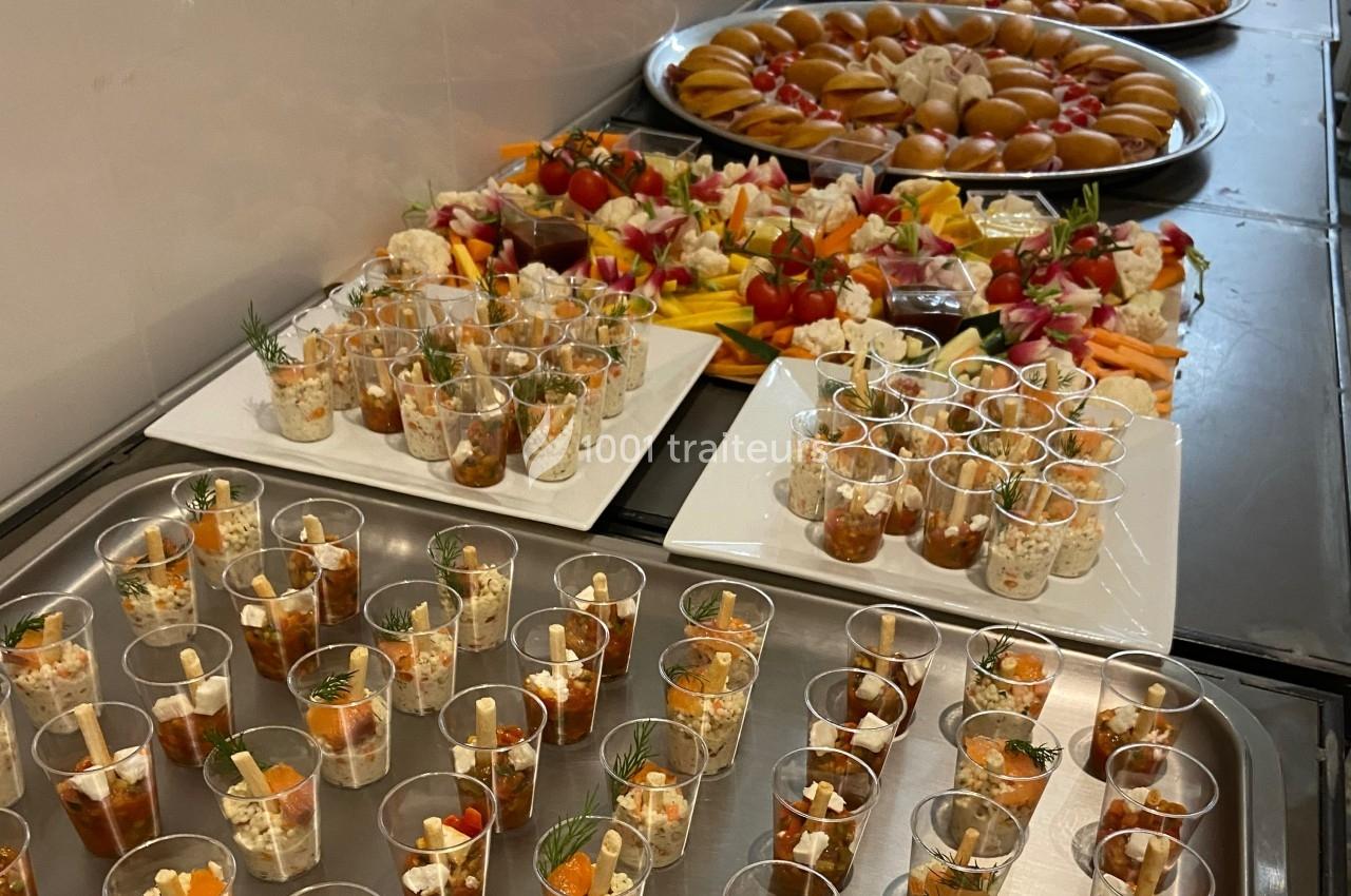 Plateaux de verrines salées et assortiments de bouchées apéritives disposés sur une table.