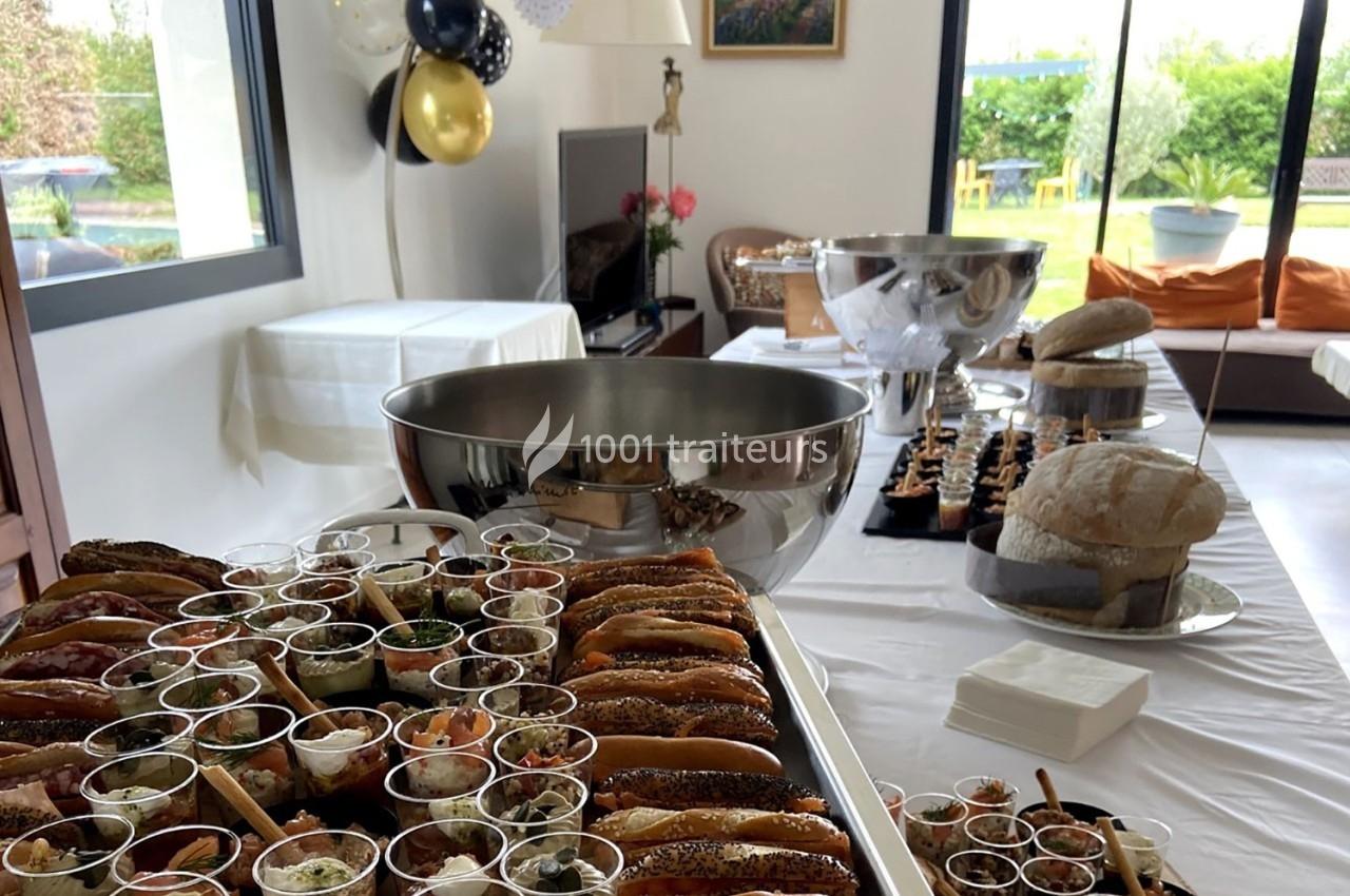 Buffet avec pains garnis, verrines et pains artisanaux, disposé dans une salle lumineuse décorée de ballons.