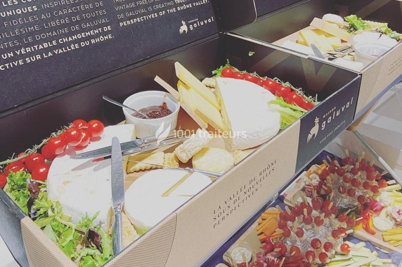 Plateaux garnis de fromages, tomates cerises, confiture et crudités, présentés dans des boîtes élégantes.