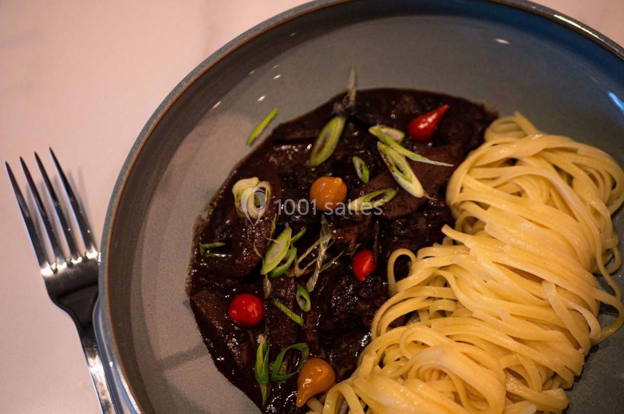 Location salle Hyères (Var) - Pasino de Hyères #8 Assiette contenant des pâtes linguine et un ragoût sombre garni de légumes et d'oignons verts émincés.