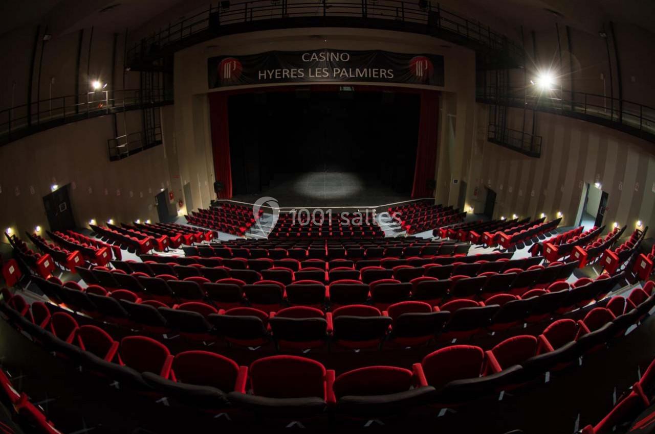 Location salle Hyères (Var) - Pasino de Hyères #4 Salle de spectacle avec rangées de sièges rouges, scène éclairée et enseigne ’Casino Hyères Les Palmiers’.