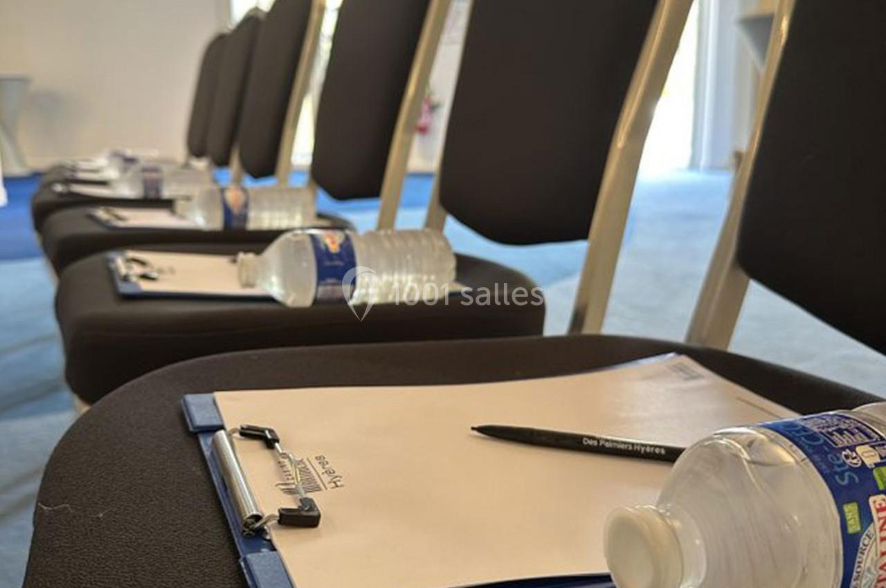 Location salle Hyères (Var) - Pasino de Hyères #3 Chaises alignées avec des blocs-notes, stylos et bouteilles d'eau posés sur chaque siège dans une salle de réunion.