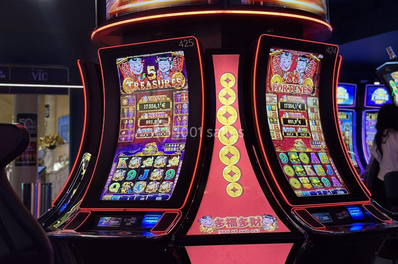 Location salle Hyères (Var) - Pasino de Hyères #16 Machines à sous lumineuses avec écrans colorés affichant des jeux et des gains potentiels dans un casino.
