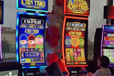 Miniature Location salle Hyères (Var) - Pasino de Hyères #17 Deux machines à sous lumineuses avec écrans colorés, une personne assise devant l'une d'elles dans un casino.