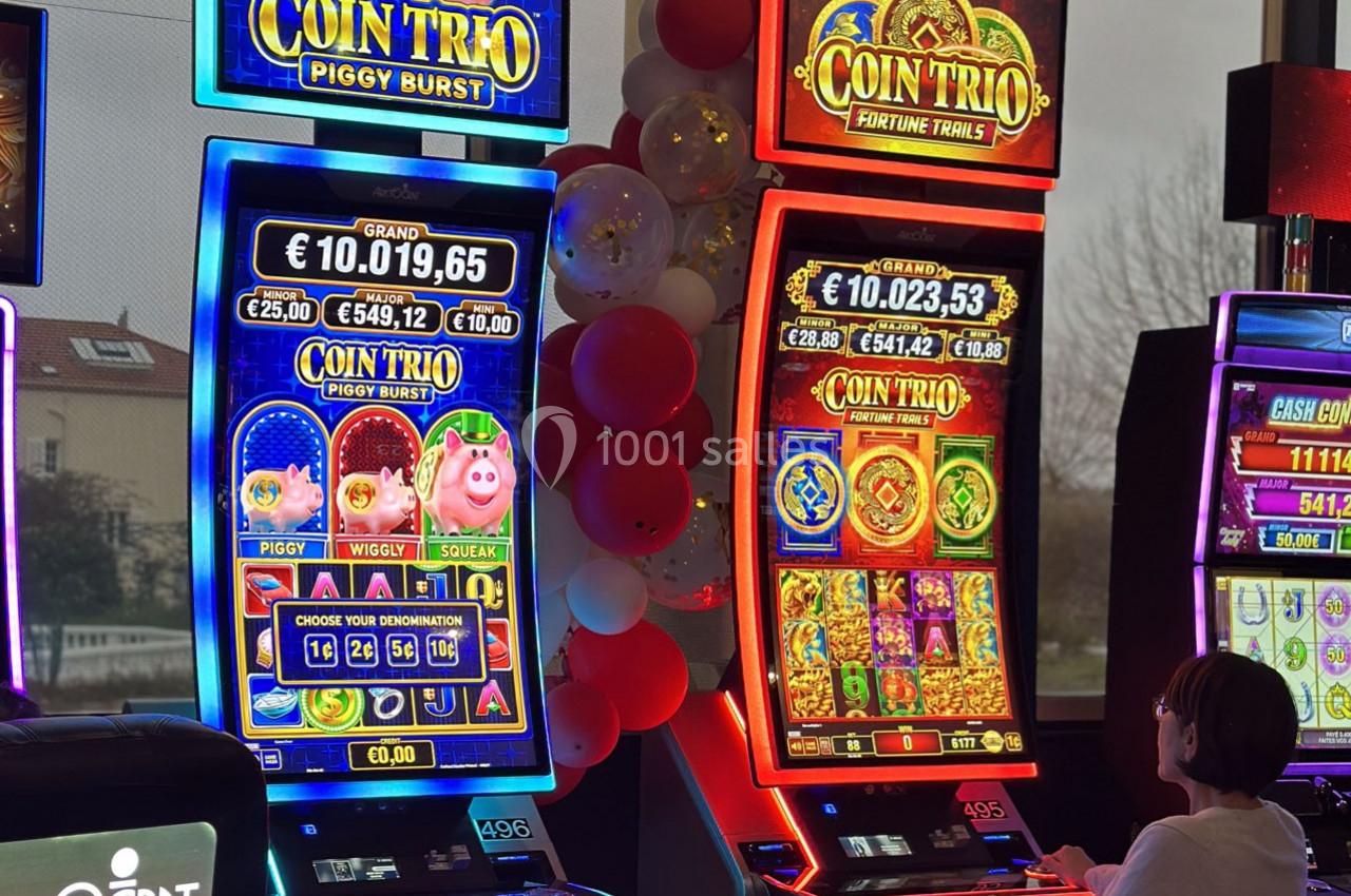 Location salle Hyères (Var) - Pasino de Hyères #17 Deux machines à sous lumineuses avec écrans colorés, une personne assise devant l'une d'elles dans un casino.