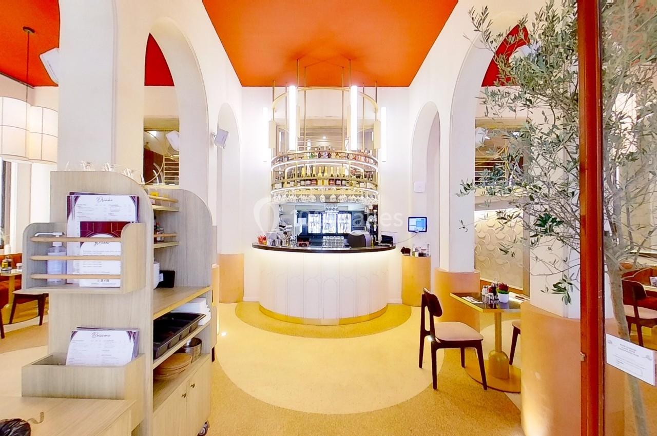 Intérieur d'un restaurant lumineux avec un comptoir central arrondi, arches blanches et plafond rouge.