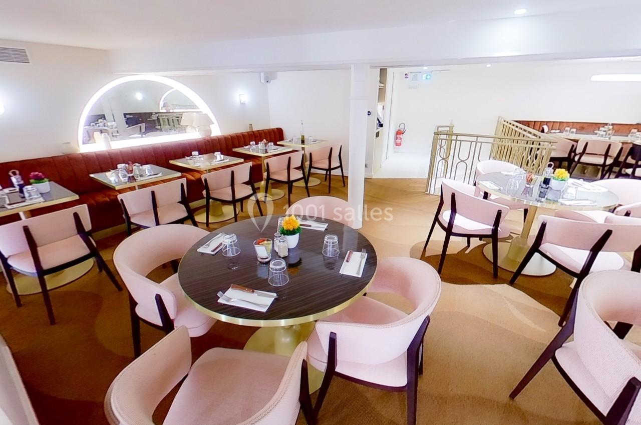 Salle de restaurant lumineuse avec tables rondes, chaises rembourrées et décoration moderne dans des tons clairs.
