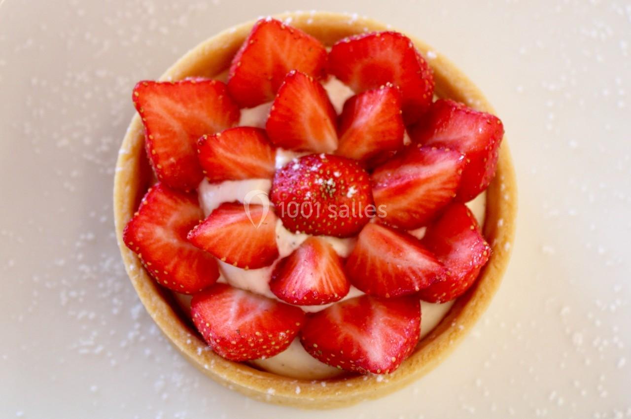 Tartelette garnie de fraises fraîches disposées en rosace sur une crème blanche, avec un fond saupoudré de sucre.