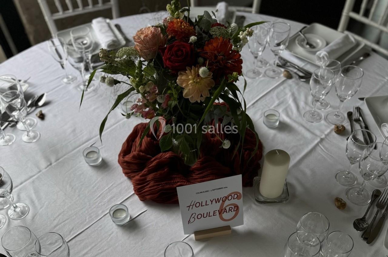 Centre de table floral avec des fleurs colorées, entouré de bougies et d'une carte ’Hollywood Boulevard’ sur une nappe…